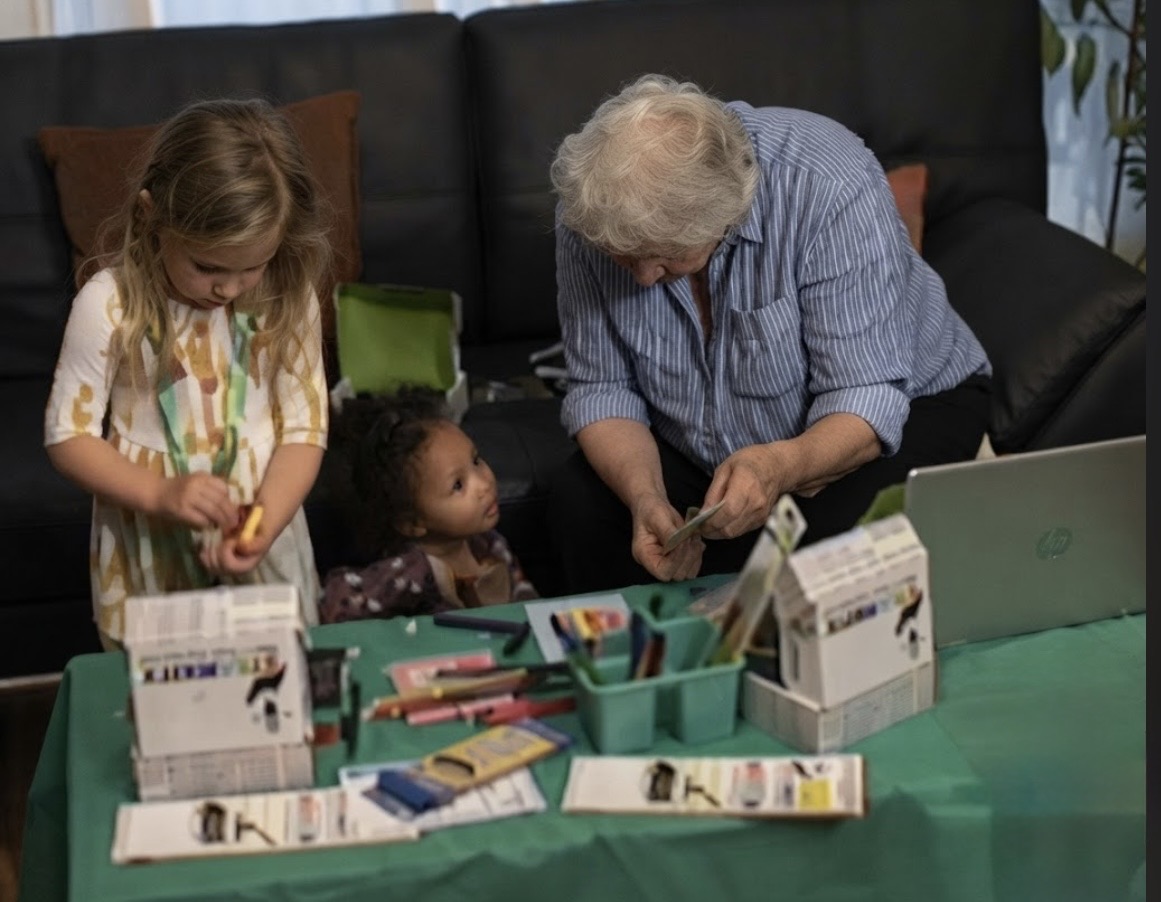 A grandparent and two young girls building STEAMKITX kits together